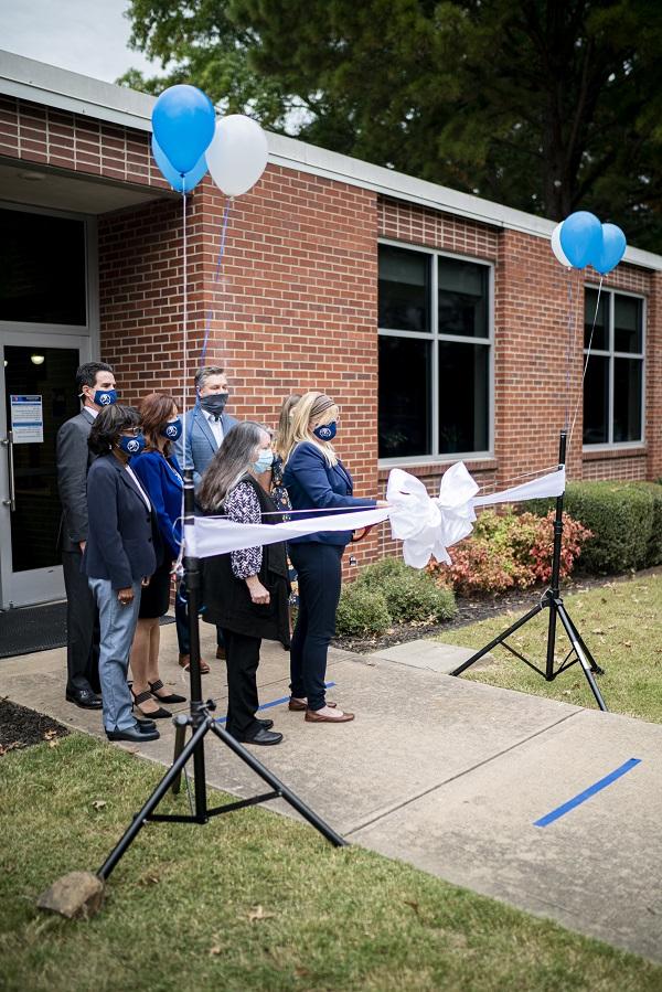 A group of UAFS administrators stand at the Writing Center front doors as Dr. Cammie Sublette and Dr. Monica Luebke cut a large white ribbon.
