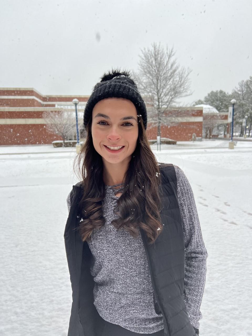 UAFS校园被雪覆盖. 伊莎贝拉穿着冬装站在校园中心附近. 她在微笑. 